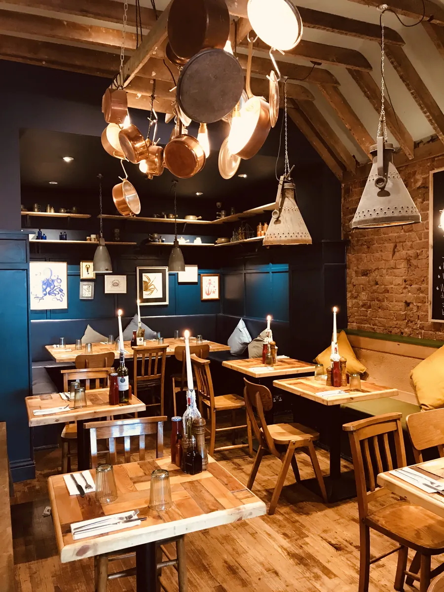 The dining room with copper pans and pendant lights over wooden tables