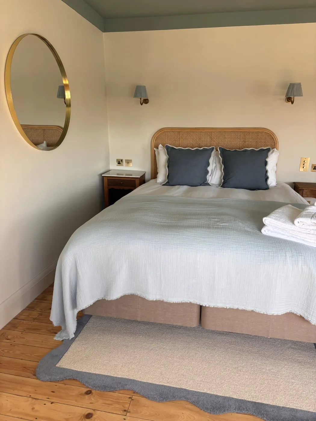 Room 9: a woven headboard, a round mirror and a blue-trimmed window