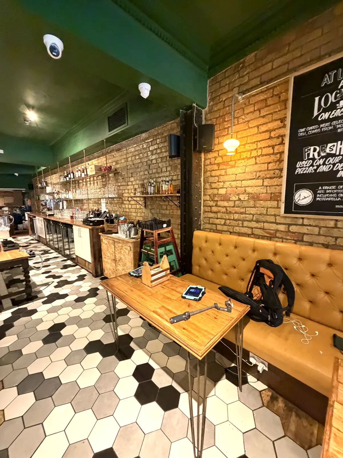 Tables by exposed brick on a hexagon-tiled floor