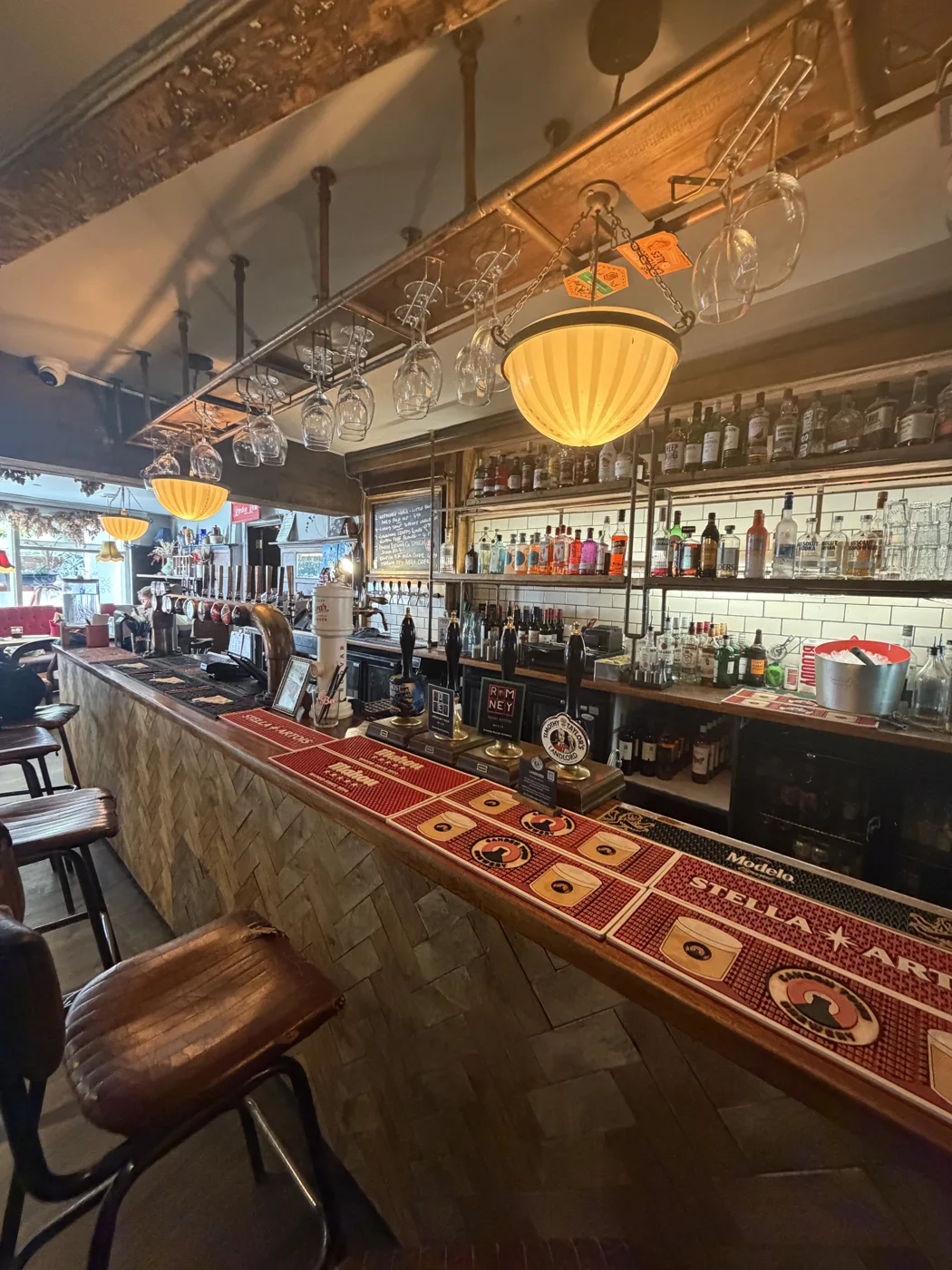 The long bar at The Pullman: red bar runners, leather stools and a back bar of bottles under glowing lamps