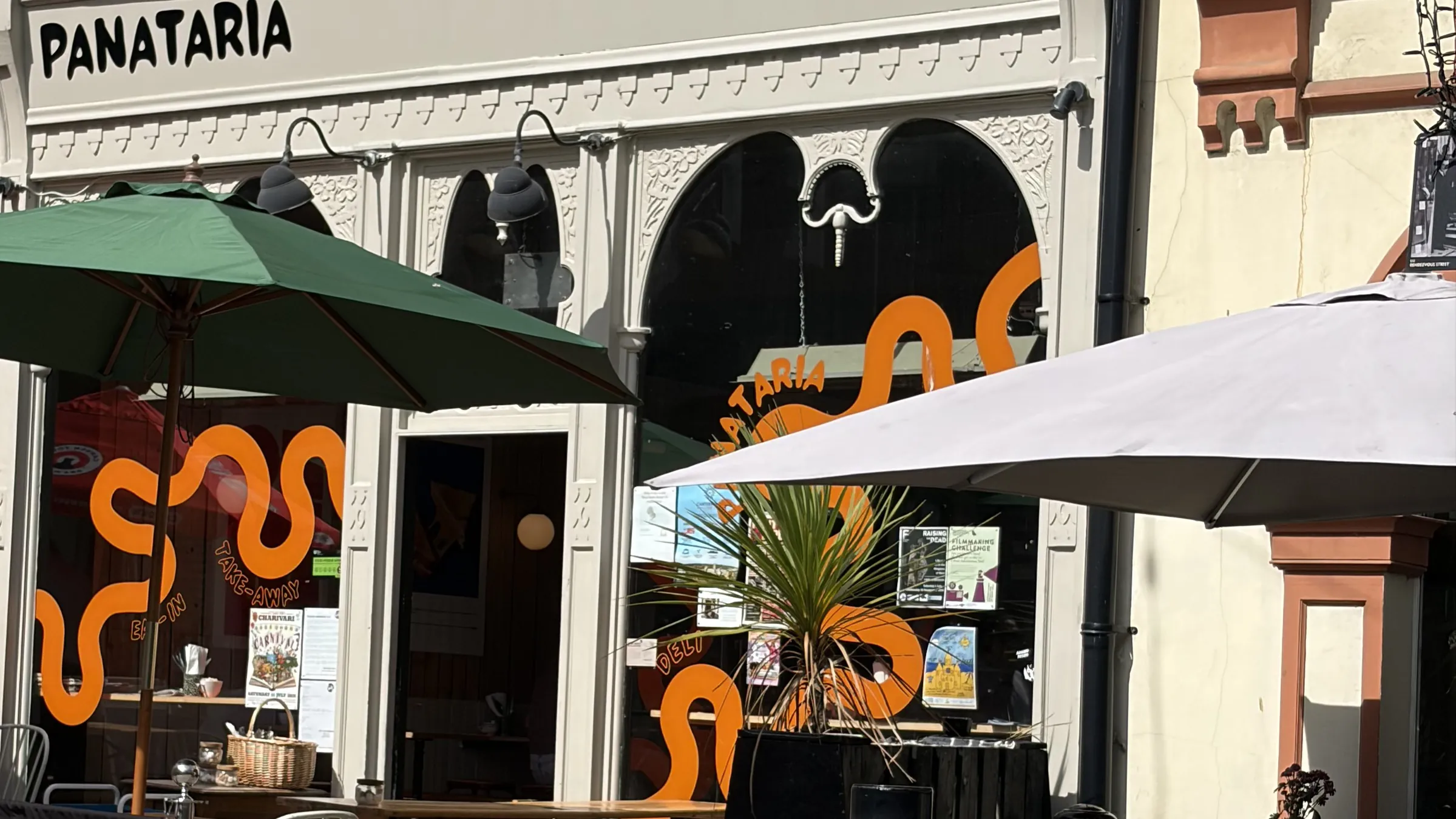 Panataria’s cream frontage with its sign, orange-wave window graphics and terrace parasols in sunshine